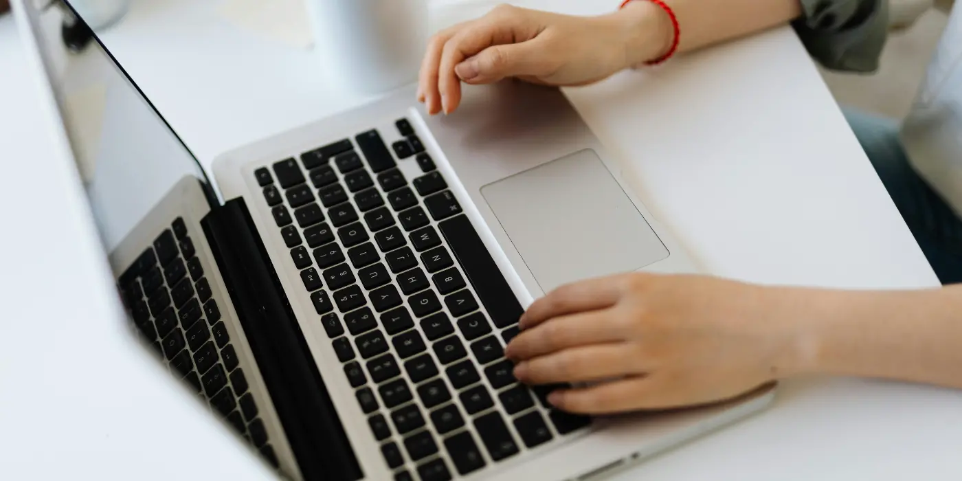 Dettaglio di mani che lavorano su un computer Mac in un ufficio luminoso del nostro Coworking a Carate Brianza.